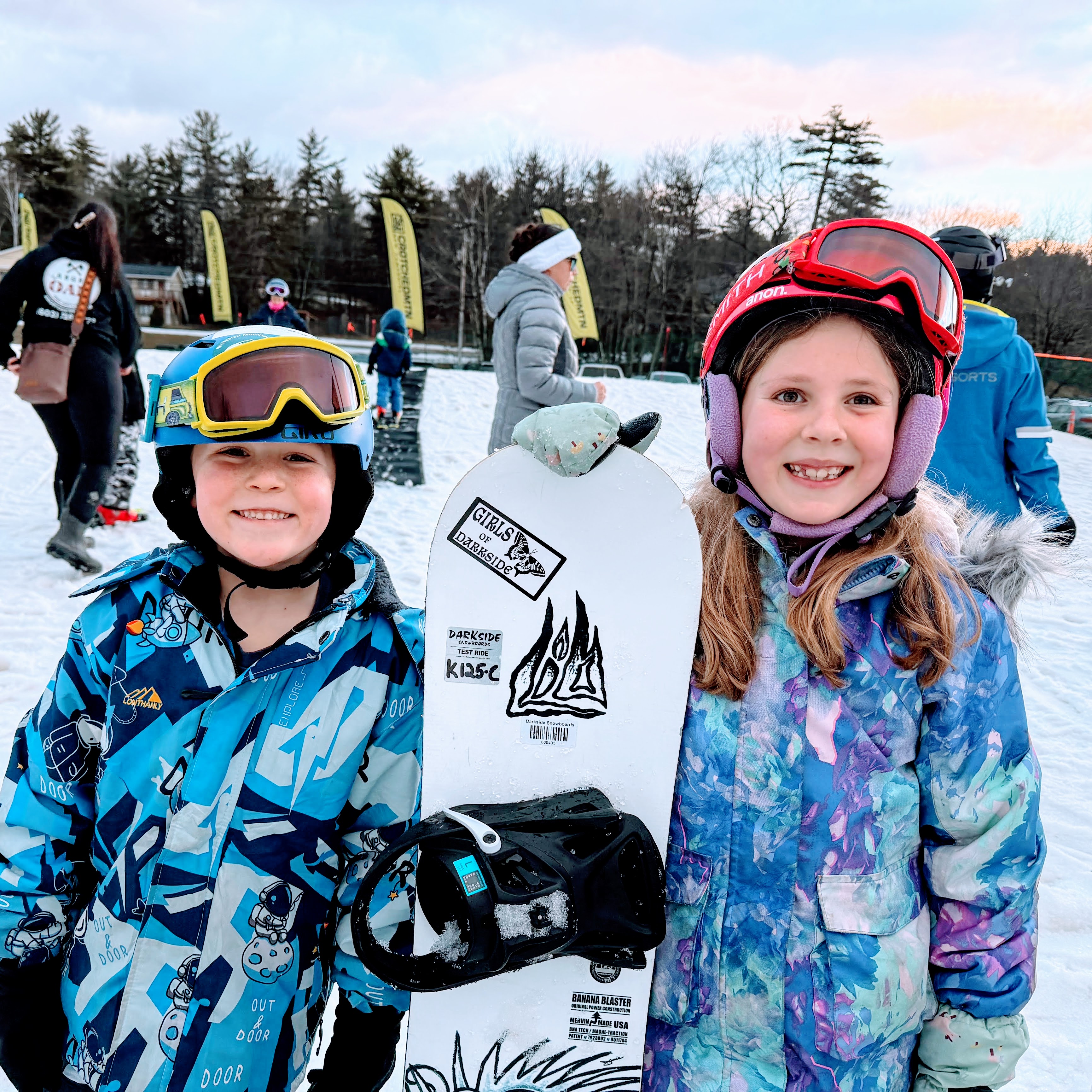 two students stand with a snowboard at Crotched Mountain Ski Area.